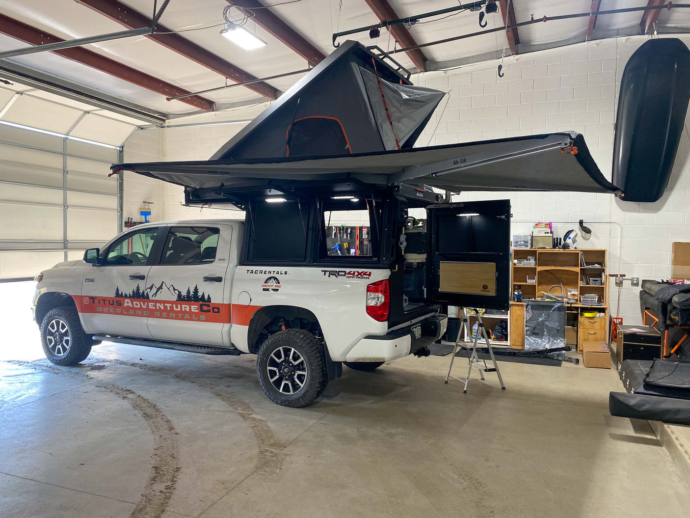 Explore off-grid with this white Toyota Tundra, a fully-equipped **RV rental** overland truck featuring a rooftop tent and camper.