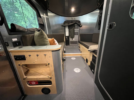 Explore this modern RV rental interior featuring versatile bench seating, a practical built-in cabinet, and natural window light.