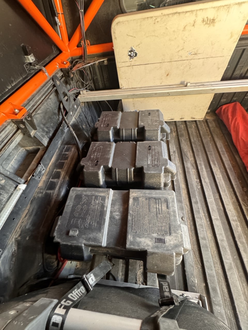 Off-road adventure vehicle bed with three portable battery boxes secured, overhead storage, and wiring. Great for RV rental trips.