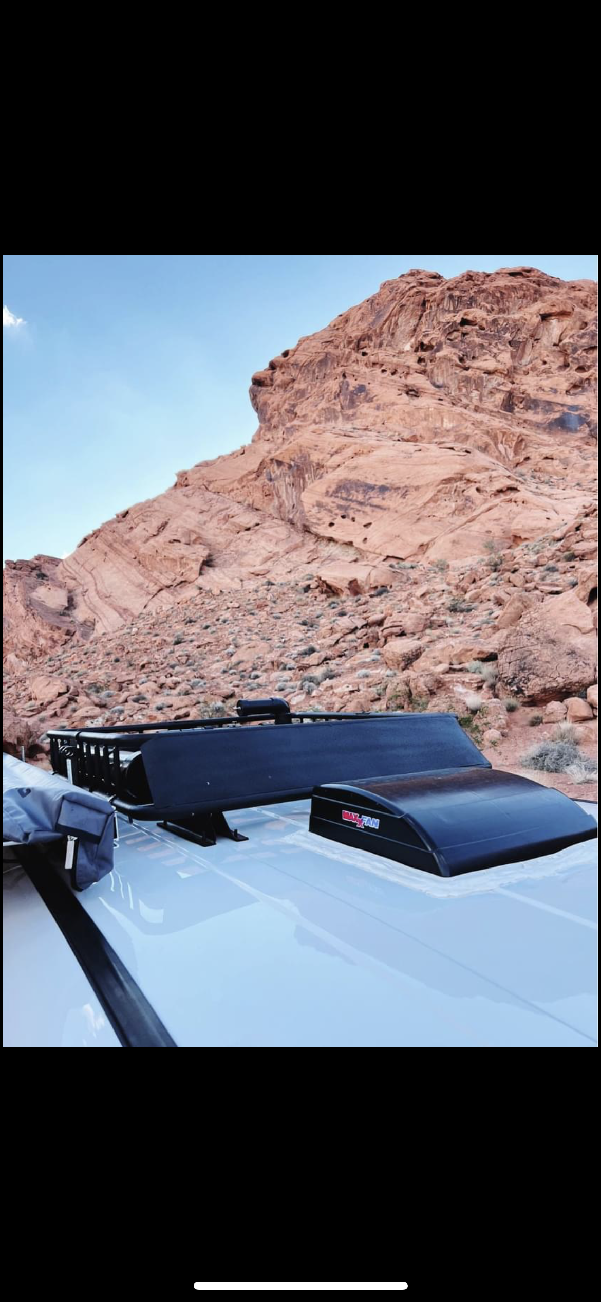 White RV rental roof with a MaxxAir fan & roof rack, set against stunning red rock mountains. Your desert adventure awaits.