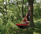 A woman unwinds in a hammock amidst lush greenery, a perfect serene spot for an RV rental getaway.