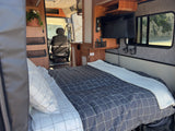 Inside a comfortable RV rental, featuring a cozy bed, TV, and a scenic view of the road from the window.