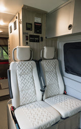 Comfortable white seats and RV control panel inside this modern RV rental for your travels.