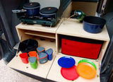 Portable camping kitchen for your rv rental adventure, featuring stove, cookware, plates, and cups. Perfect for outdoor meals.