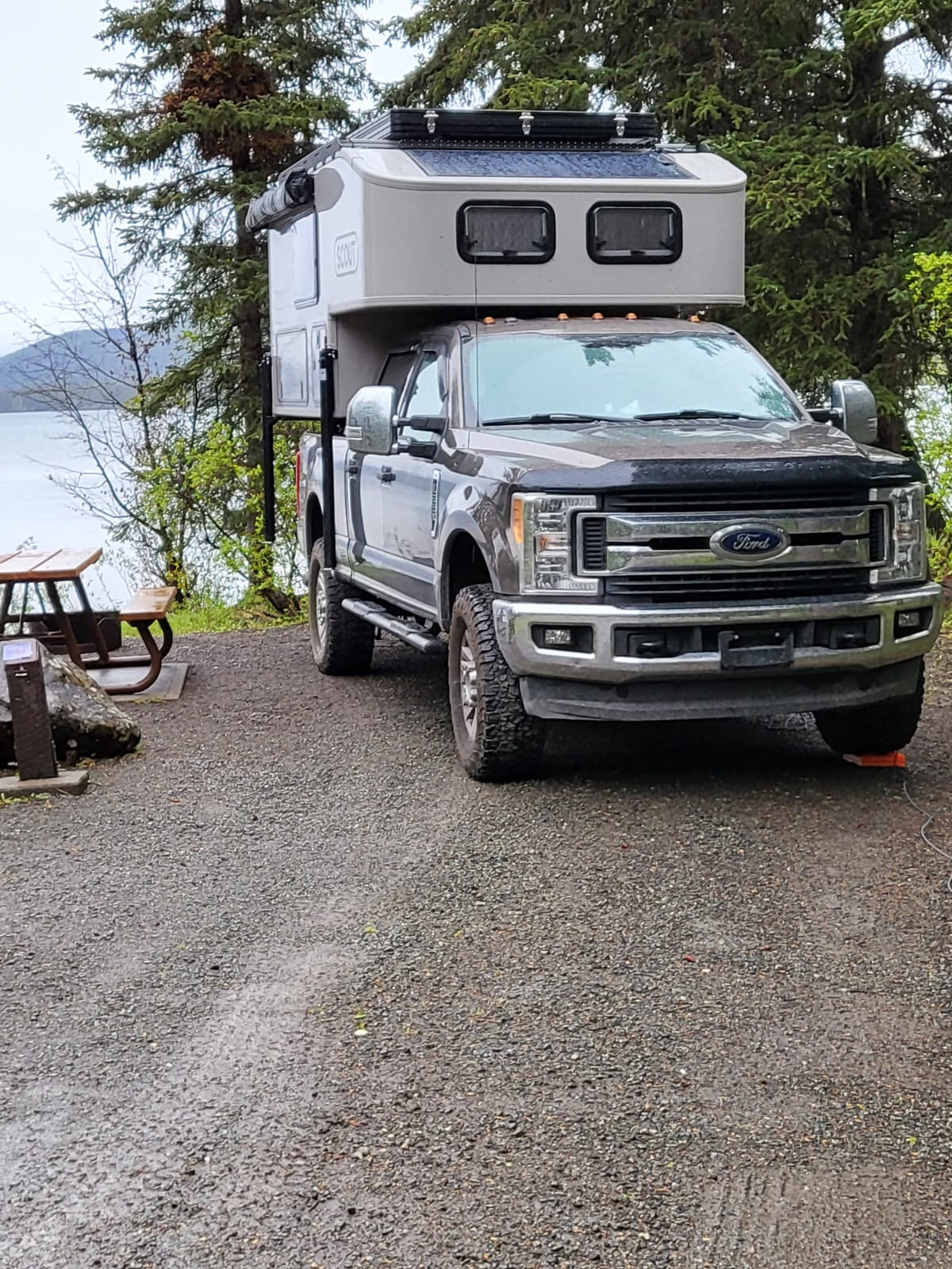  set up by a scenic river with mountains in the background.|This RV rental — photo 2