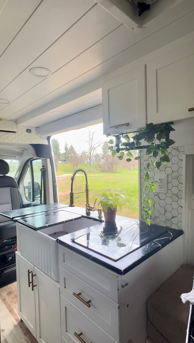 This RV rental kitchen features a modern sink, cooktop, and ample storage for comfortable mobile living. — photo 9