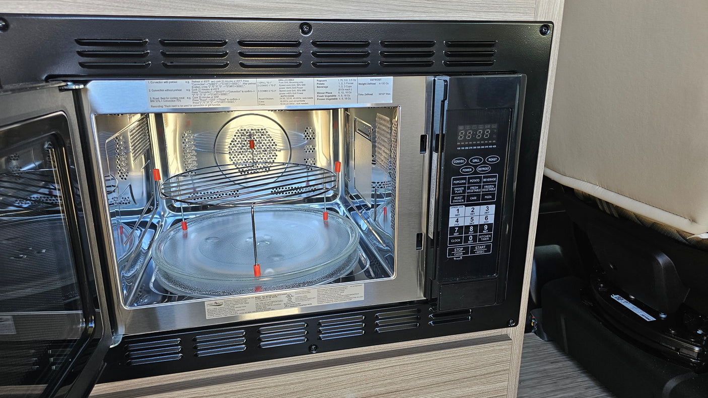 Inside an **rv rental**, an open **microwave oven** reveals its interior and control panel, highlighting multi-functional cooking.