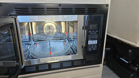 Inside an **rv rental**, an open **microwave oven** reveals its interior and control panel, highlighting multi-functional cooking.