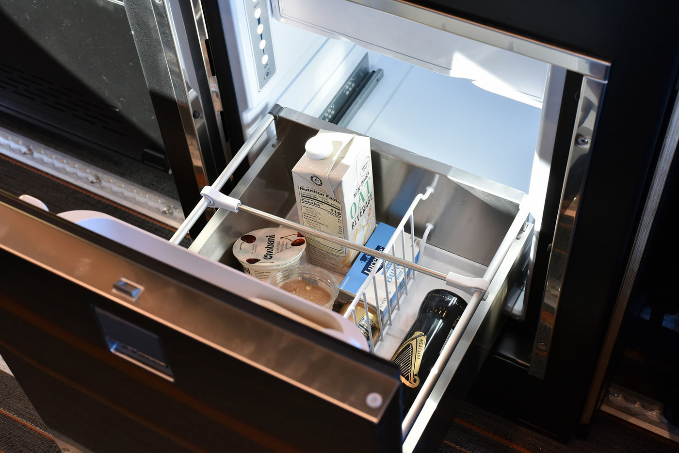 RV rental mini-fridge open, revealing oat milk, Chobani yogurt, butter, and a Guinness bottle. Convenient food storage on the go. — photo 6