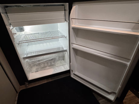 Inside this RV rental: an empty, well-lit refrigerator with freezer and door compartments.