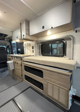 This cozy rv rental interior features a kitchenette, overhead cabinets, bench seating with integrated storage, and durable flooring.