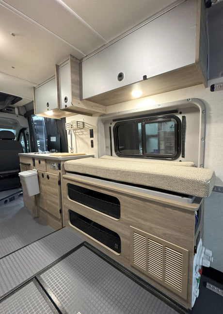 This cozy rv rental interior features a kitchenette, overhead cabinets, bench seating with integrated storage, and durable flooring.
