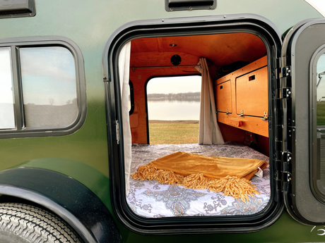 Step into this cozy RV rental camper with a comfortable bed and stunning lakeside view, perfect for a nature escape.
