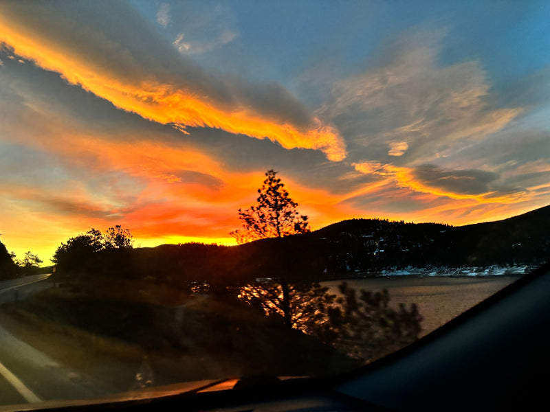 A stunning orange & red sunset over a serene lake, framed by silhouetted mountains & trees. Ideal view from an RV rental trip. — photo 16