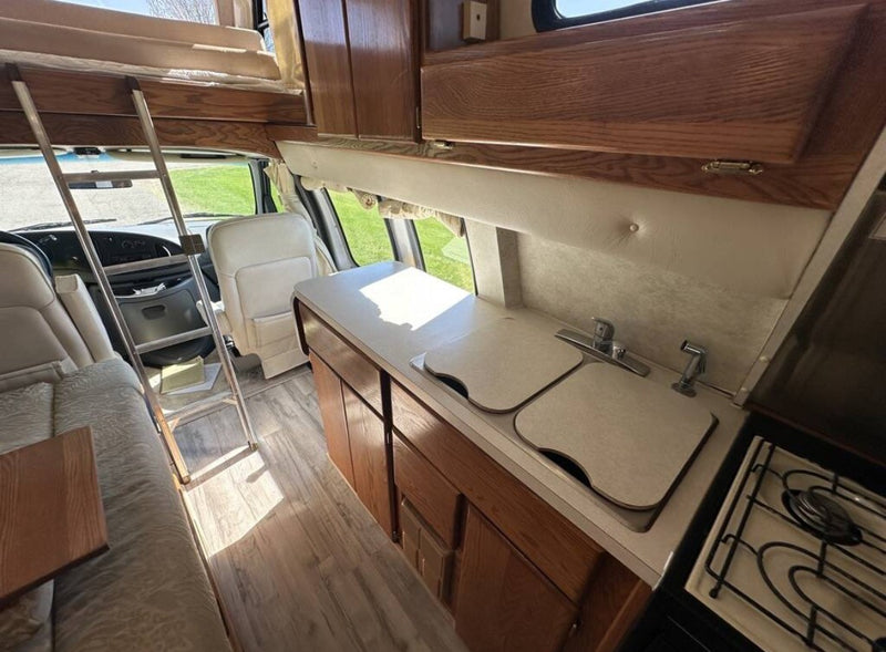 Interior of an rv rental showing a bright kitchenette, bunk bed, and front seats. Ready for your next road trip adventure. — photo 14