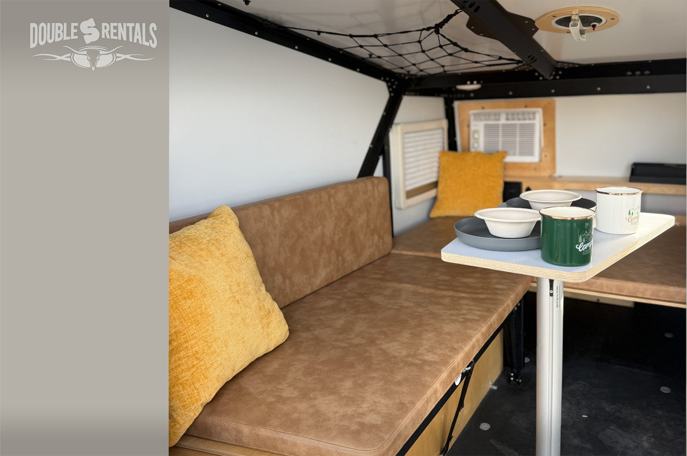 Cozy RV rental interior with bench seating, a small dining table, and air conditioning for comfortable travel.