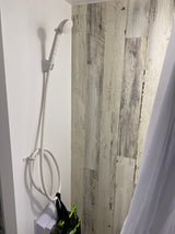 Compact shower with white handheld head & hose in an RV rental bathroom, offering convenience for travel.
