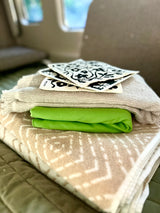 RV rental essentials: neatly stacked towels, green fabric, and eco-friendly patterned cleaning cloths for travel.