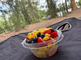 Fresh fruit salad with berries & pineapple on a dark mat outdoors, perfect for an RV rental adventure.