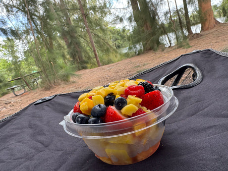 Fresh fruit salad with berries & pineapple on a dark mat outdoors, perfect for an RV rental adventure.