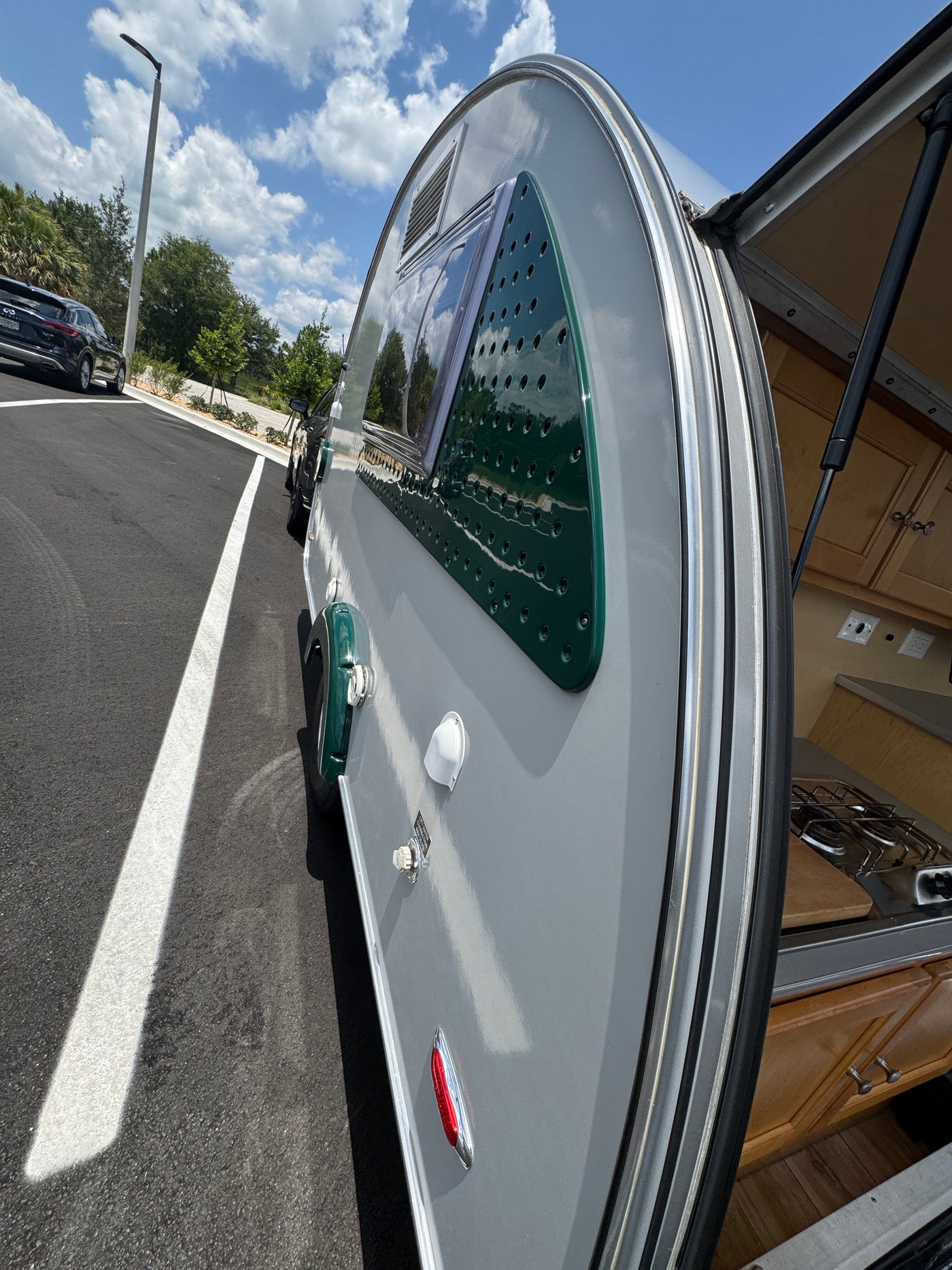 Explore with this stylish gray and green teardrop RV rental! Rear hatch open reveals compact kitchen; parked on asphalt. — photo 7
