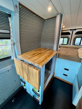 RV rental: Stylish camper van interior with compact kitchen, folding table, hidden shower, and comfy bed for mobile living.