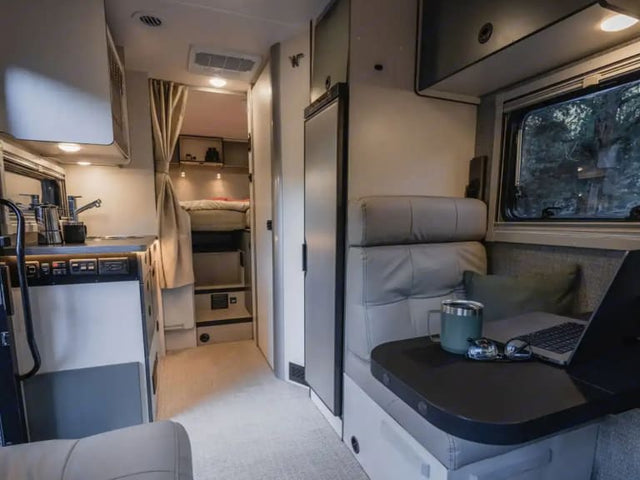  parked on sand.|Modern rv rental interior featuring a compact kitchen