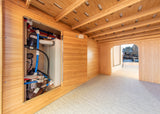 RV rental utility space: A clean bamboo-lined compartment holds the water tank & plumbing system under a slatted bed frame.