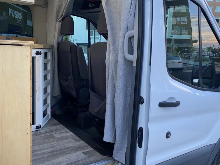 RV rental van's open side door reveals its custom interior: seating, wood-look floor, and cabinetry. — photo 16