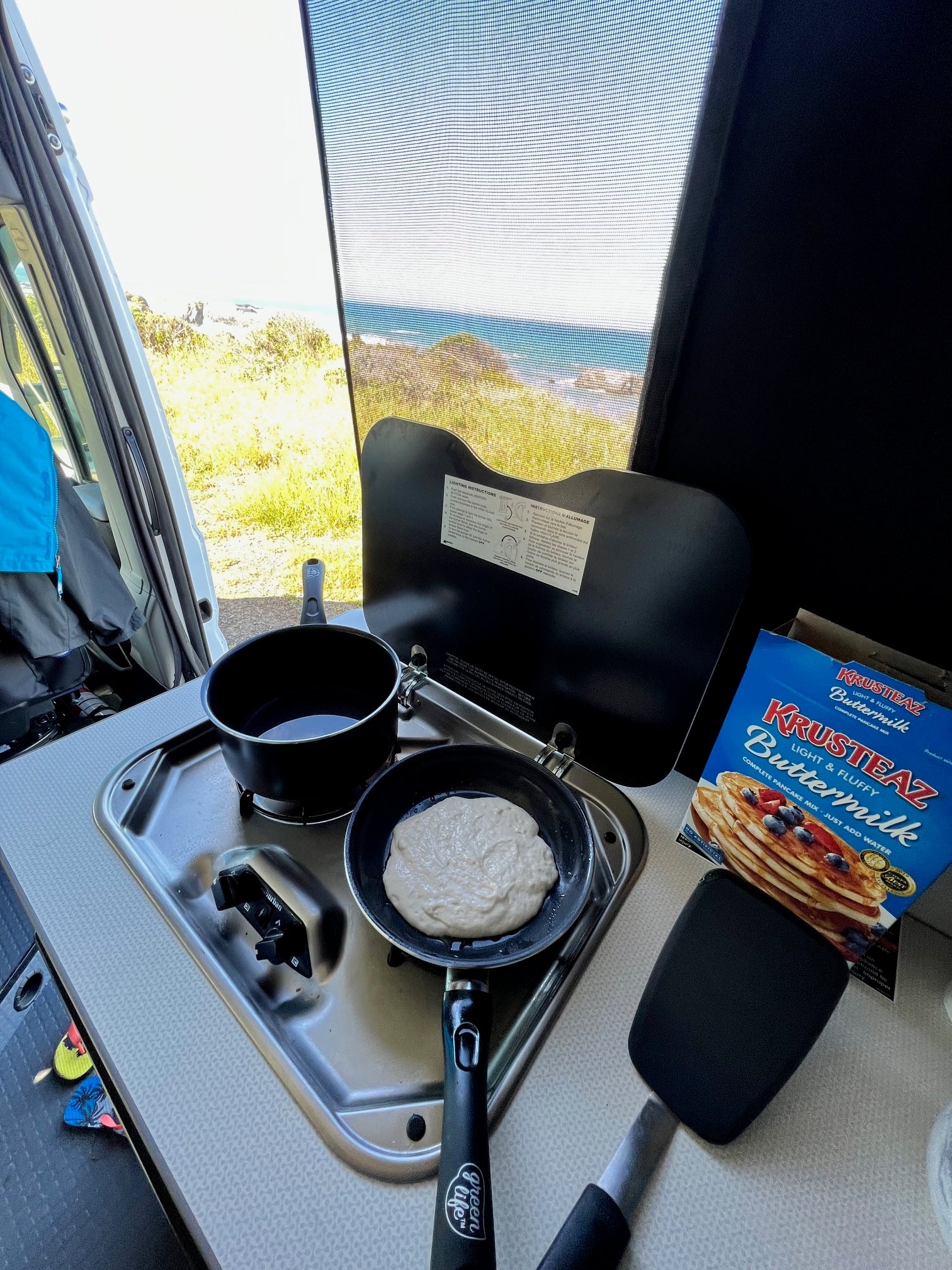 RV rental breakfast: Pancakes cooking on the stovetop with a beautiful ocean view.