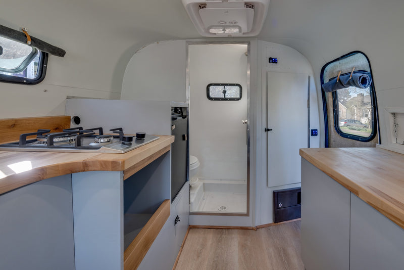 Explore this RV rental's interior: a compact kitchenette, a shower, and bright windows define this cozy camper. — photo 19