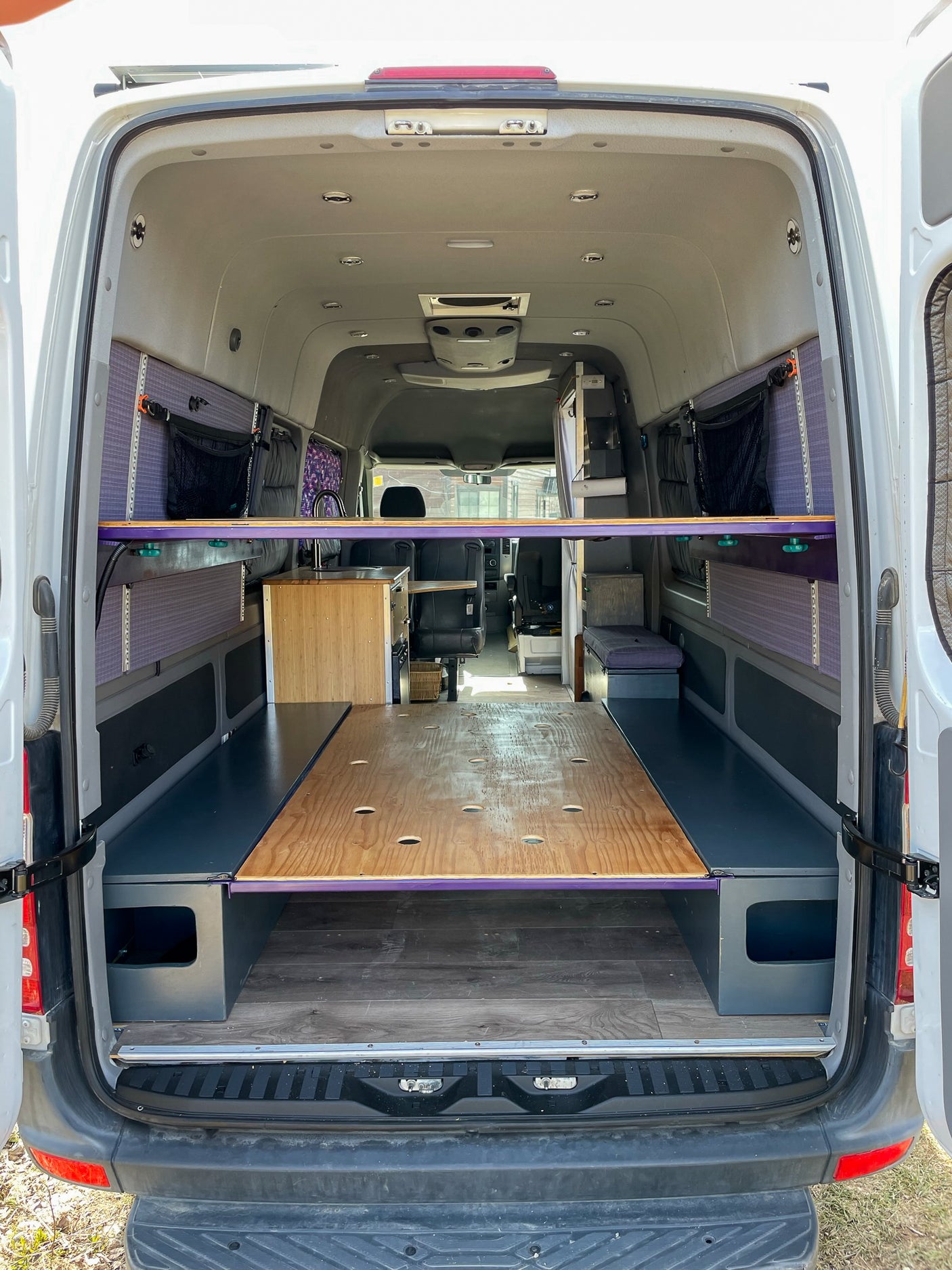 Custom RV rental interior: A fully equipped camper van, showcasing a modular bed, kitchen, & smart storage for van life.
