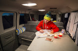Cozy RV rental interior: Woman reads map by candlelight. Perfect for a road trip adventure.