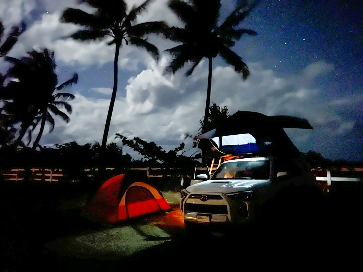 Night camping adventure with an RV rental! White SUV with rooftop tent, orange ground tent, and palm trees under starry clouds. — photo 13