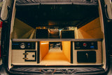 Organized storage in this RV rental camper van rear features illuminated pull-out drawers, utility panels, and cubbies.