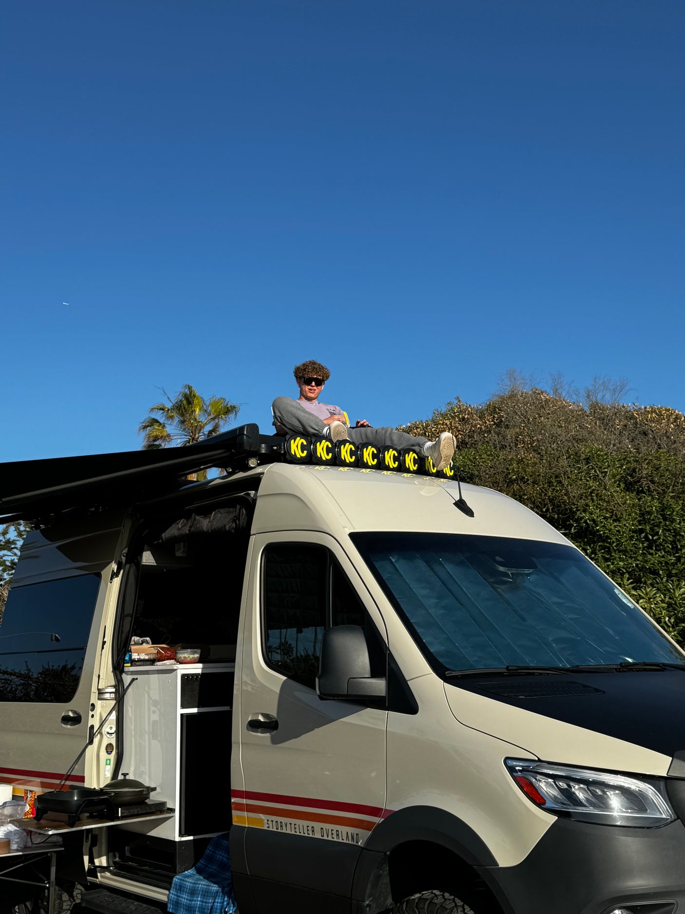Relaxing on a Storyteller Overland RV rental with outdoor kitchen, enjoying sunny van life.