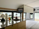 Experience the freedom of an RV rental: a stylish bus conversion with a full kitchen, bed, and stunning lake views.