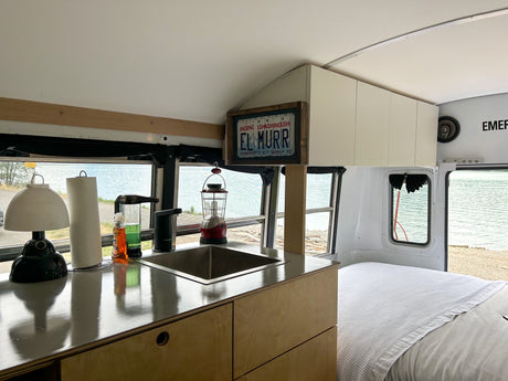Experience the freedom of an RV rental: a stylish bus conversion with a full kitchen, bed, and stunning lake views.