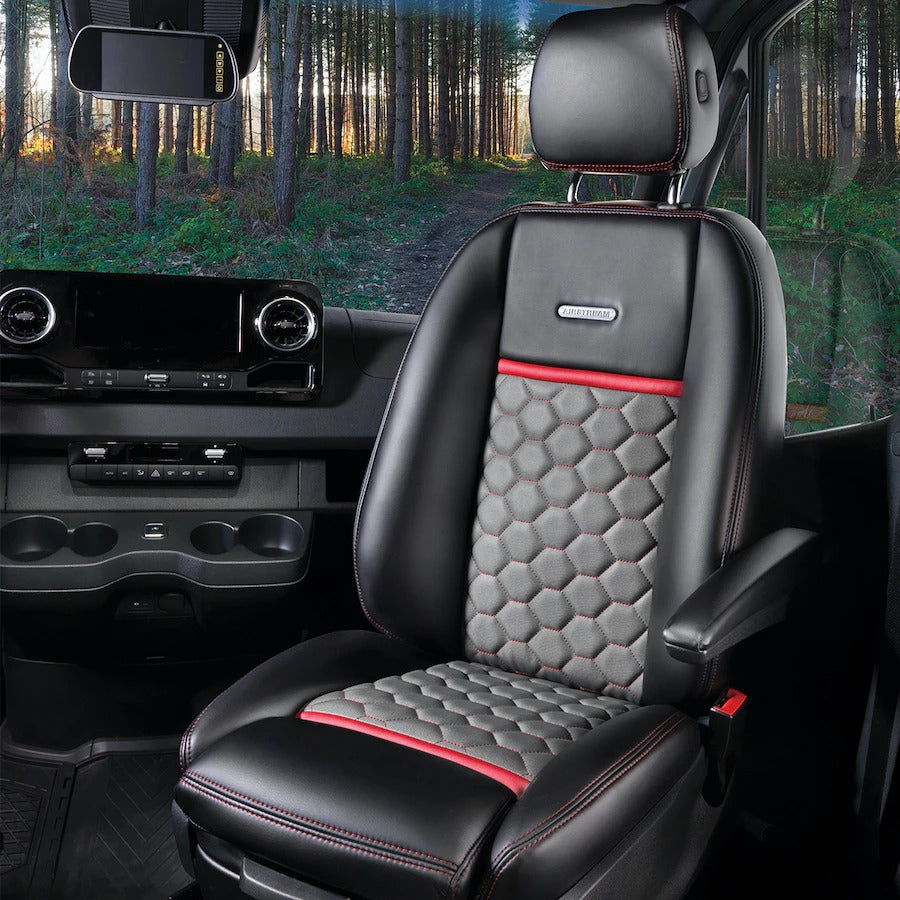 Experience this RV rental's plush black & red Airstream interior. Quilted seat, dash, & forest road ahead.