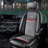 Experience this RV rental's plush black & red Airstream interior. Quilted seat, dash, & forest road ahead.
