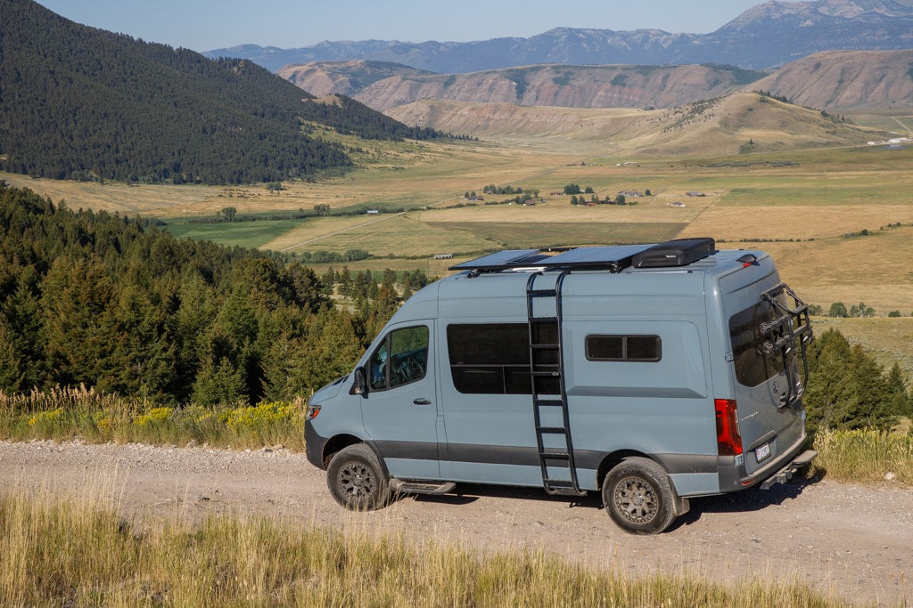  with panoramic mountain range views. Ideal for an RV rental trip.|A grey camper van (rv rental) with solar panels on a dirt road — photo 2