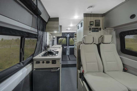 Spacious RV rental interior showcasing a kitchenette, two passenger seats, and rear cargo access, perfect for road trips.