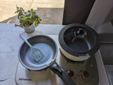 Compact RV rental kitchen setup: Stove, pan, pot, and spatula for easy on-the-go cooking and meals.