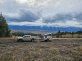 Truck & overland trailer (an adventure RV rental) parked with stunning Grand Teton mountain views.