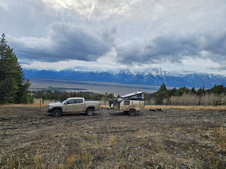 Truck & overland trailer (an adventure RV rental) parked with stunning Grand Teton mountain views.