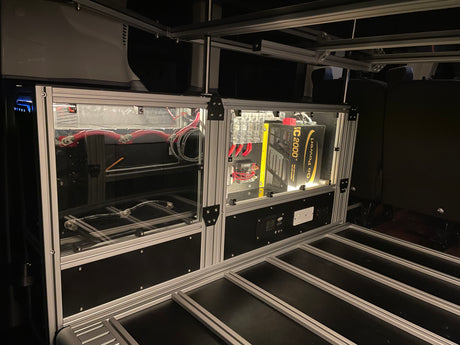 Inside an rv rental, a custom electrical system: Go Power inverter, battery setup, fuse blocks, and monitor display, built with aluminum extrusion.