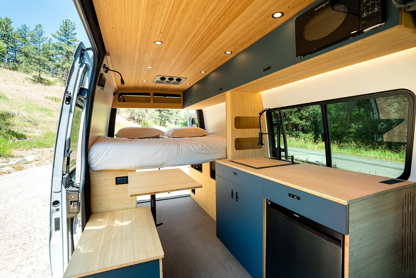 Modern RV rental interior featuring a cozy bed, full kitchen, and flexible dining table for comfortable road trips. — photo 4