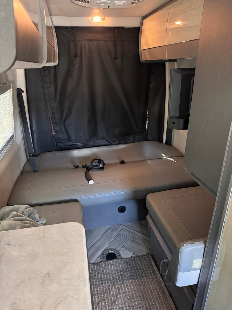 Cozy RV rental interior with convertible dinette/bed, overhead storage, and integrated fridge. — photo 10