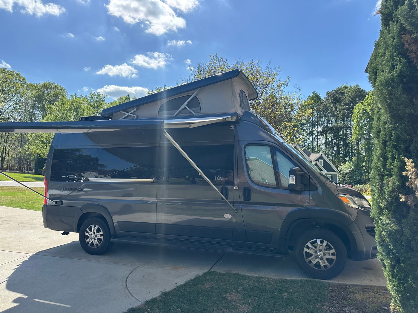 Gray camper van RV rental with pop-top roof and awning extended — photo 1