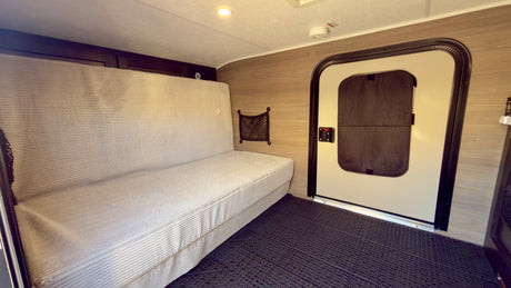 Inside an RV rental: a cozy sofa bed, entrance door, and textured floor. Perfect for compact living on the road.
